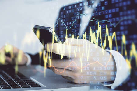 Multi exposure of mans hands holding and using a digital phone and forex graph drawing. Financial...