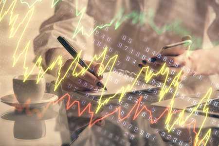 Double exposure of financial graph sketch hologram and woman holding and using a mobile device....