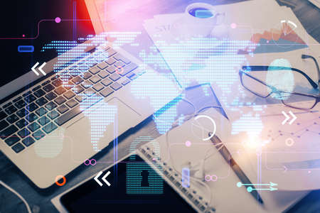Double exposure of desktop with computer and world map hologram. International data network concept.