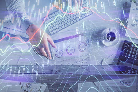 Multi exposure of man's hands typing over a computer keyboard and forex graph hologram drawing. Top...