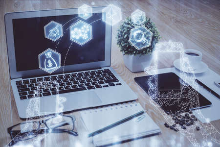 Computer on desktop in office with technology theme hologram. Double exposure. Tech concept.