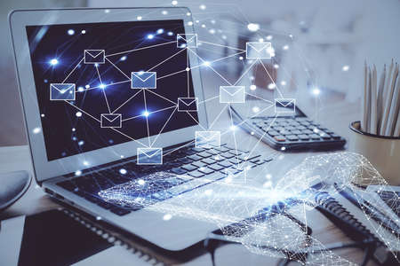 Desktop computer background in office and flying envelops hologram drawing. Double exposure. Electronic mail concept.の写真素材