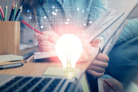 Bulb hologram over hands taking notes background. Concept of idea. Double exposure