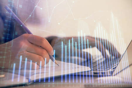 Double exposure of businesswoman hands typing on computer and forex chart hologram drawing....