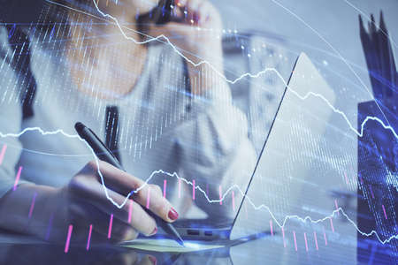 Double exposure of woman hands typing on computer and financial graph hologram drawing. Stock market...