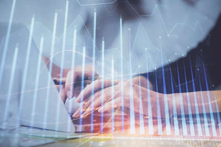 Multi exposure of woman hands typing on computer and financial graph hologram drawing. Stock market...