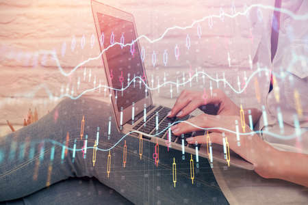 Multi exposure of woman hands typing on computer and forex chart hologram drawing. Stock market...