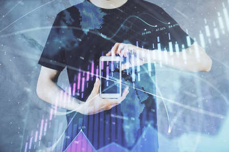 Double exposure of mans hands holding and using a digital device and forex graph drawing. Financial...