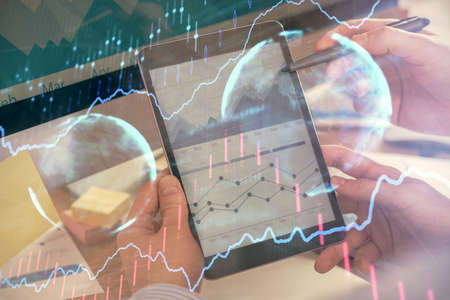 Double exposure of mans hands holding and using a phone and financial chart drawing. Market analysis...