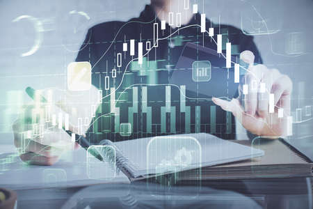 Double exposure of man hands holding a credit card and Forex graph drawing. Stock trading and...