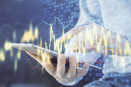 Double exposure of mans hands holding and using a digital device and forex graph drawing. Financial...