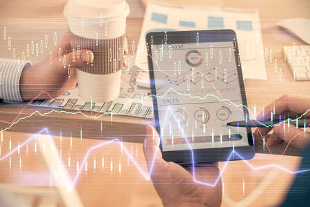 Double exposure of mans hands holding and using a phone and financial chart drawing. Market analysis...