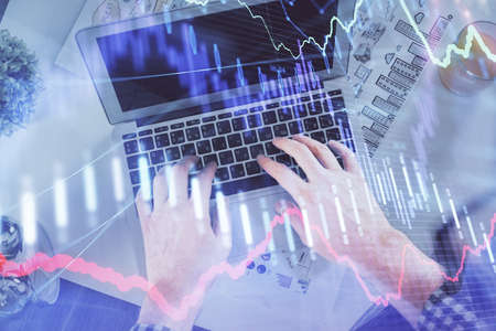 Double exposure of mans hands typing over laptop keyboard and forex chart hologram drawing. Top view. Financial markets concept.の写真素材