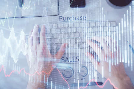 Double exposure of mans hands typing over laptop keyboard and forex chart hologram drawing. Top...