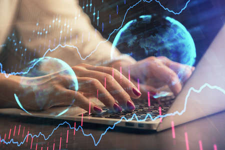 Double exposure of businesswoman hands typing on computer and forex chart hologram drawing....