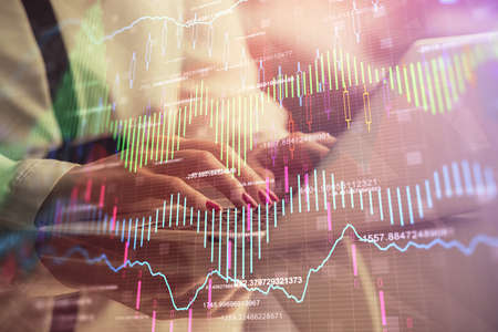 Double exposure of businesswoman hands typing on computer and financial graph hologram drawing....