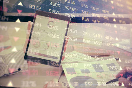 Double exposure of mans hands holding and using a digital device and forex graph drawing. Financial...