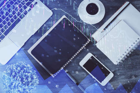 Double exposure of forex chart hologram over desktop with phone. Top view. Mobile trade platform...