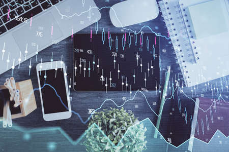 Double exposure of forex chart hologram over desktop with phone. Top view. Mobile trade platform concept.の写真素材