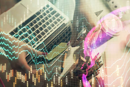 Double exposure of businesswoman hands typing on computer and financial graph hologram drawing....
