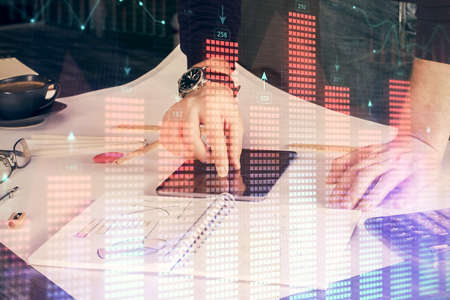 Double exposure of mans hands holding and using a digital device and forex graph drawing. Financial...