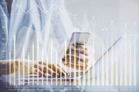 Double exposure of financial graph sketch hologram and woman holding and using a mobile device....