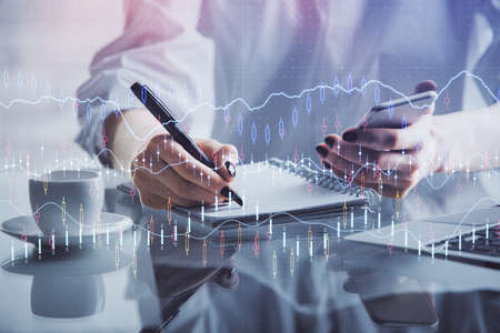 Double exposure of financial graph sketch hologram and woman holding and using a mobile device....