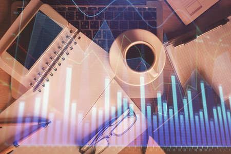 Double exposure of financial graph hologram over desktop with phone. Top view. Mobile trade platform...