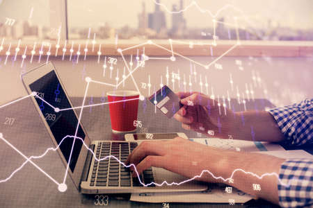 Double exposure of man hands holding a credit card and Forex graph drawing. Stock trading and...