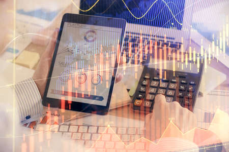 Double exposure of mans hands holding and using a digital device and forex graph drawing. Financial...