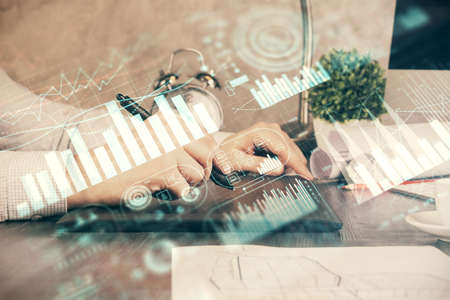 Double exposure of mans hands holding and using a phone and financial graph drawing. Analysis...