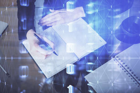 Double exposure of writing hands on background with data solution hologram on front. Technology...