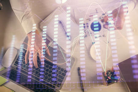 Multi exposure of mans hands typing over computer keyboard and forex graph hologram drawing. Top...