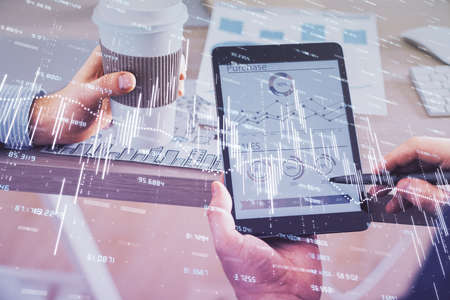 Double exposure of mans hands holding and using a phone and financial chart drawing. Market analysis...
