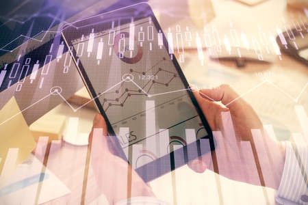 Double exposure of mans hands holding and using a phone and financial graph drawing. Analysis...