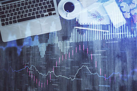 Financial market graph and top view computer on the desktop background. Double exposure. Investment...