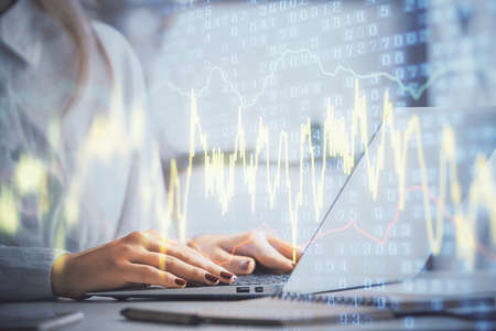 Double exposure of woman hands working on computer and forex graph hologram drawing. Financial...