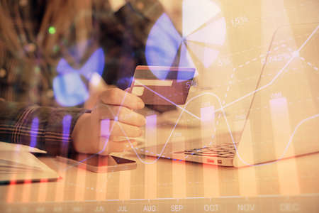 Multi exposure of woman on-line shopping holding a credit card and financial graph drawing. Stock...