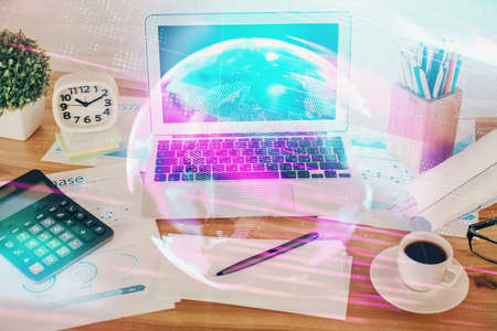 Computer on desktop in office with technology theme hologram. Double exposure. Tech concept.