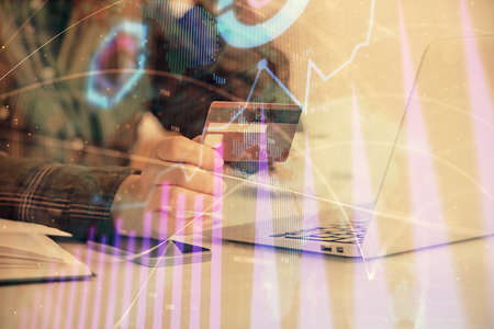 Multi exposure of woman on-line shopping holding a credit card and financial graph drawing. Stock...