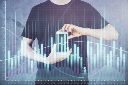 Double exposure of mans hands holding and using a digital device and forex graph drawing. Financial...