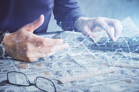 Double exposure of mans hands holding and using a digital device and forex graph drawing. Financial...
