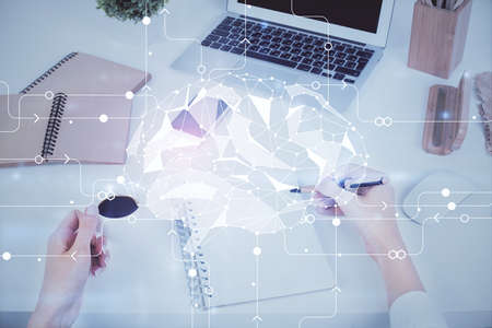 Double exposure of womans writing hand on background with brain hud. Concept of learning.
