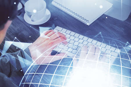 Double exposure of world map hologram with man working on computer on background. Concept of...