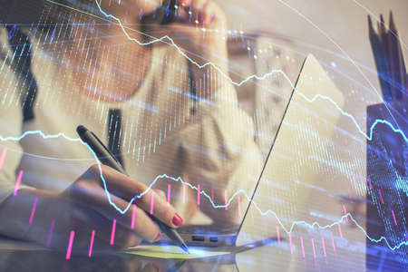 Double exposure of woman hands typing on computer and financial graph hologram drawing. Stock market...