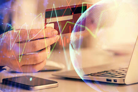 Multi exposure of woman on-line shopping holding a credit card and financial graph drawing. Stock...