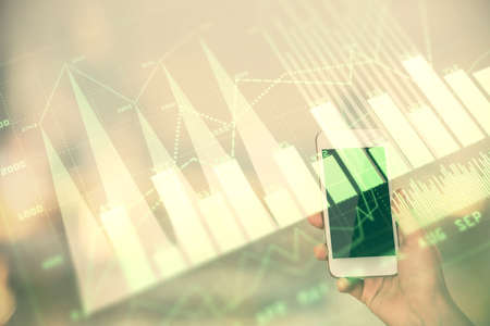 Double exposure of forex chart sketch hologram and woman holding and using a mobile device. Stock...
