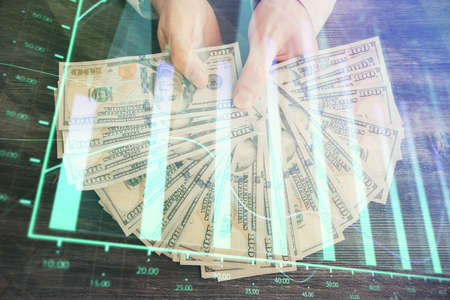 Multi exposure of financial graph drawing hologram and USA dollars bills and man hands. Analysis...