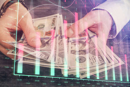 Multi exposure of financial graph drawing hologram and USA dollars bills and man hands. Analysis...