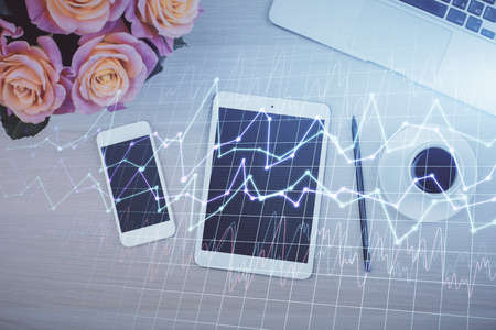 Double exposure of forex graph hologram over desktop with phone. Top view. Mobile trade platform...